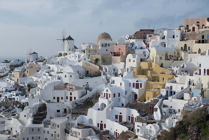 Santorini, Greece Beautiful city of Oia on a hill of white houses with blue  roof and windmills against dramatic pink sky, located in Greek Cyclades