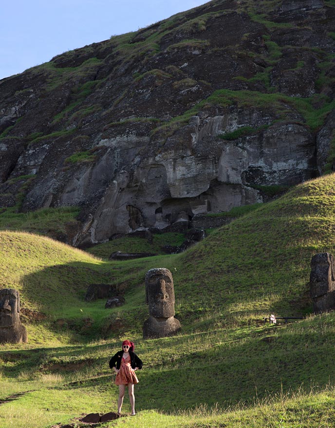 tourists posing with moai statue sculptures